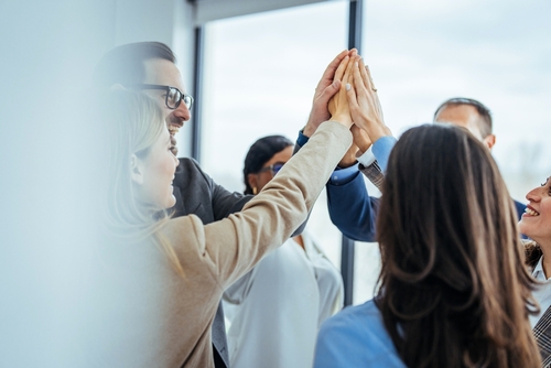 Team,Celebrating,Success,With,High,Five,In,Office,Environment